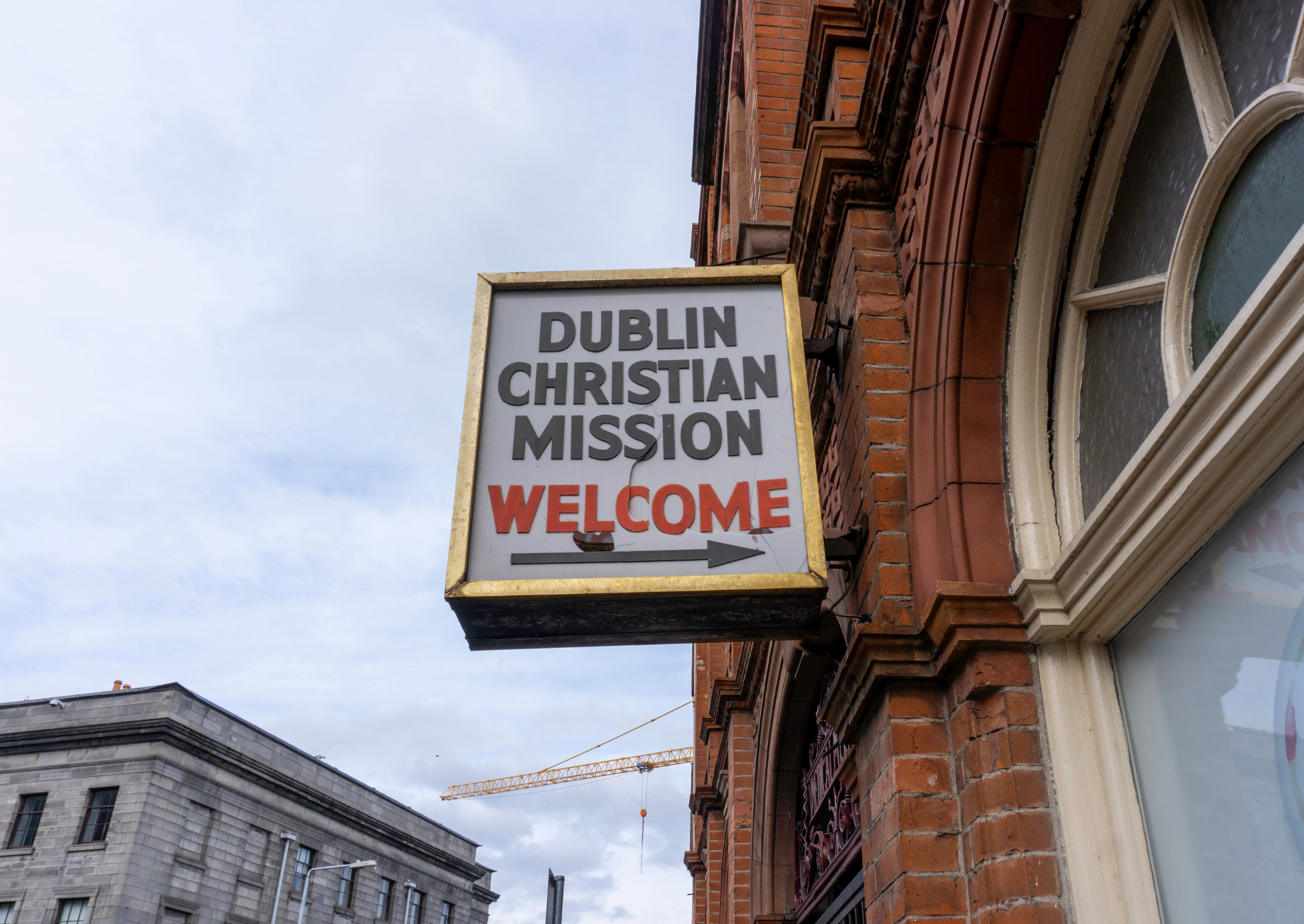 sign hanging in a brick wall saying Dublin Christian Mission Welcome