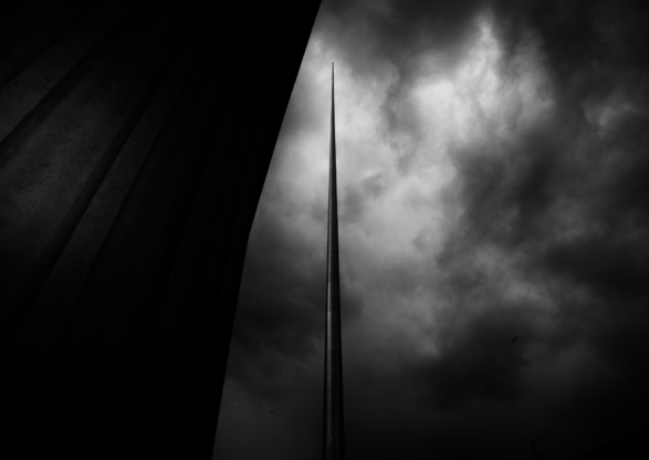 A view of the spire on O'Connell street from a low angle looking up. It is darkened and cloudy around the rest of the sky